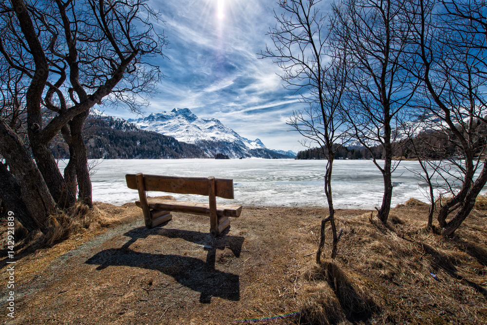 Wooden bench to admire the scenery on an alpine lake ice