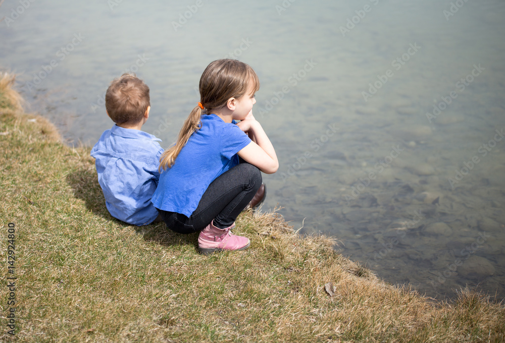 Fototapeta premium Siblings sitting by the lake.