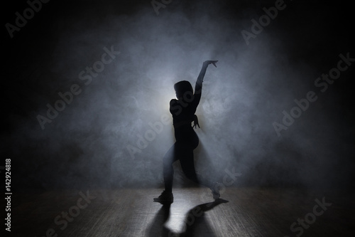 Hip-hop dancer posing backlit.