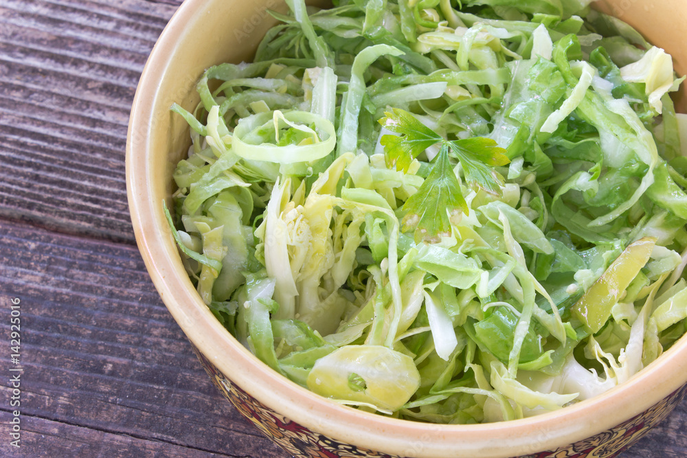 Sliced young cabbage salad in ceramic bowl on table Sliced young cabbage salad in ceramic bowl on table