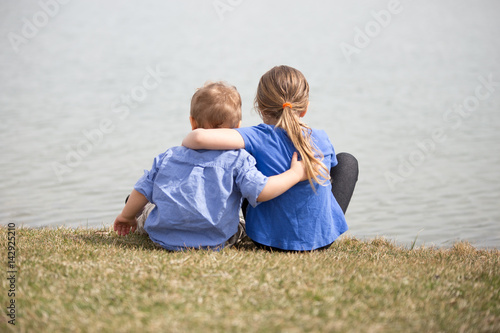 Young sibling boy and girl holding eachothr.