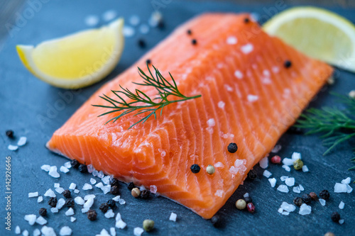 Raw salmon lemon salt and pepper on the background of the black stone