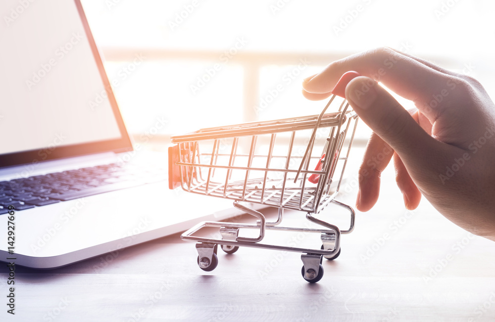 Online shopping concept with hand and cart