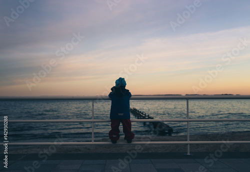 Kind genießt den Sonnenuntergang an der Promenade von Travemünde