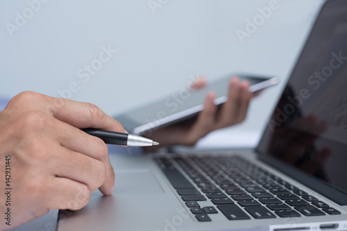 Businessman holding pen and using tablet computer