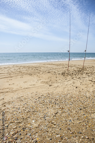 Two fishing rods hammered on the beach sand