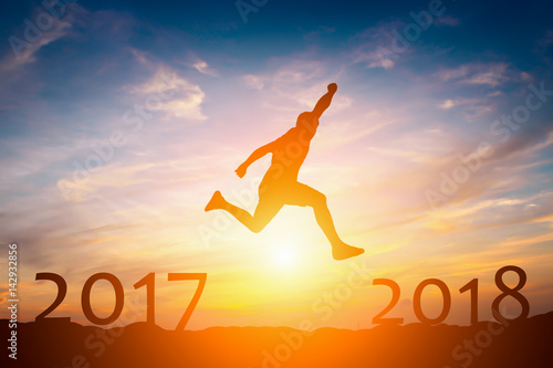 Silhouette of man jump from 2017 to 2018 success concept in sunset