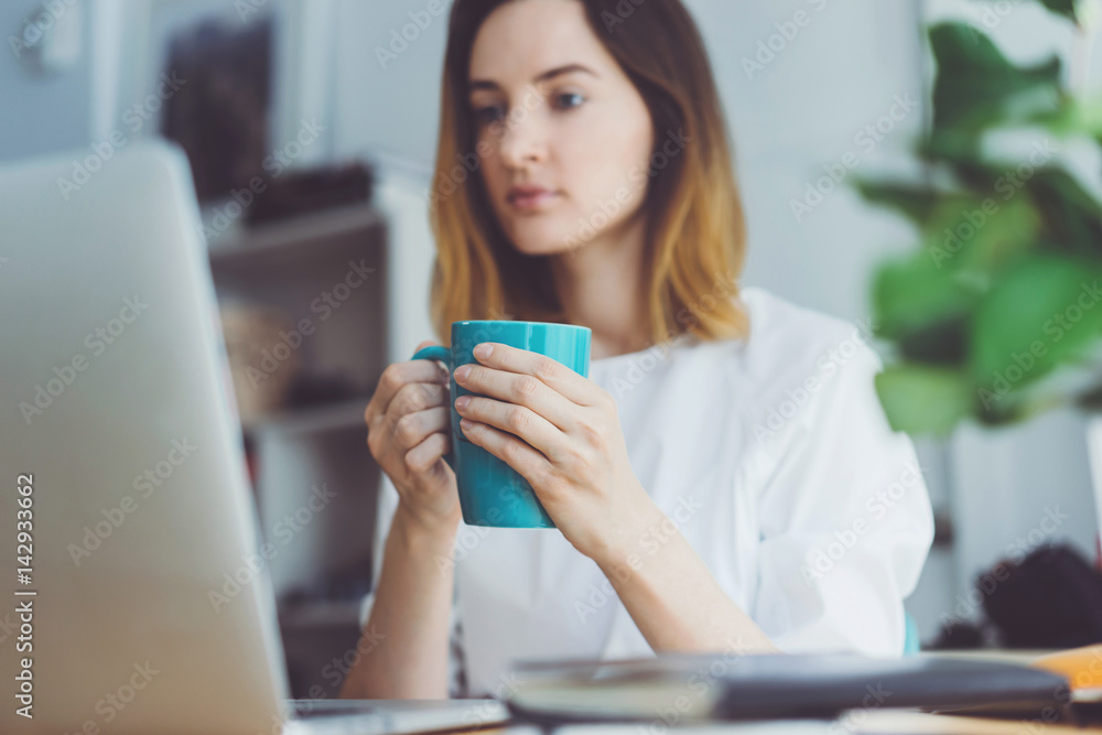 Young businesswoman working at modern office on portable computer, Attractive female drinking coffee while working at office Young businesswoman working at modern office on portable computer, Attractive female drinking coffee while working at office
