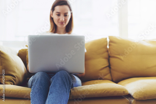 Attractive female is typing messages on a laptop while sitting at home, Hipster girl working on a portable computer from home