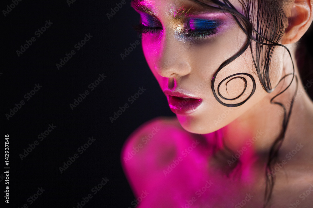 Young beautiful girl bright makeup with a wet look shine, dark background, pink light, disco style Young beautiful girl bright makeup with a wet look shine, dark background, pink light, disco style