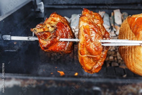 A large piece of Pork ham meat is cooked on an open fire in the grill. Street Czech food