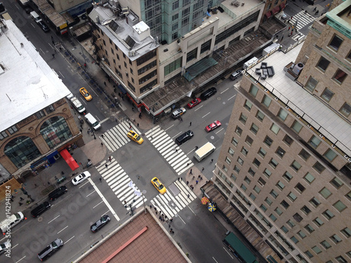 Bird's eye view of 5th Avenue from tall New York City skyscraper. Busy Manhattan intersection. New York yellow taxis and people crossing busy city intersection. Urban New York life. Looking down.