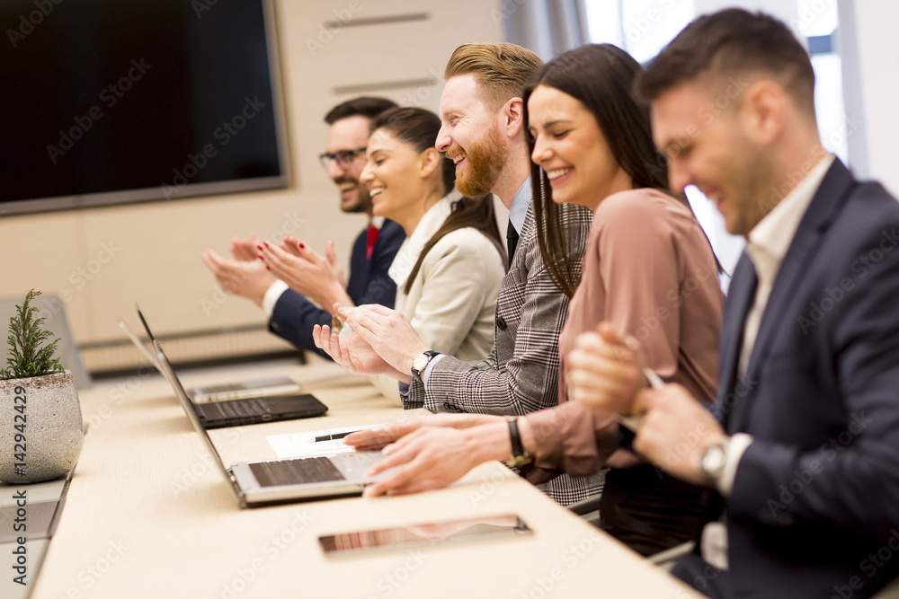 Happy smiling business team clapping hands during a meeting in office Happy smiling business team clapping hands during a meeting in office