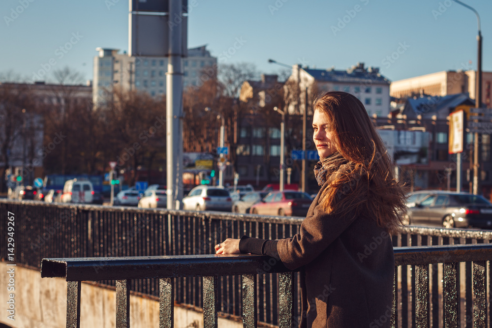 Young attractive girl in a coat in the city at sunset