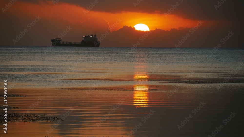 Ship at sunset. The sun sets over the sea at the Fishing Base in Garapan, Saipan. 
