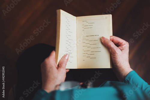 Old woman reading a book with russian poetry
