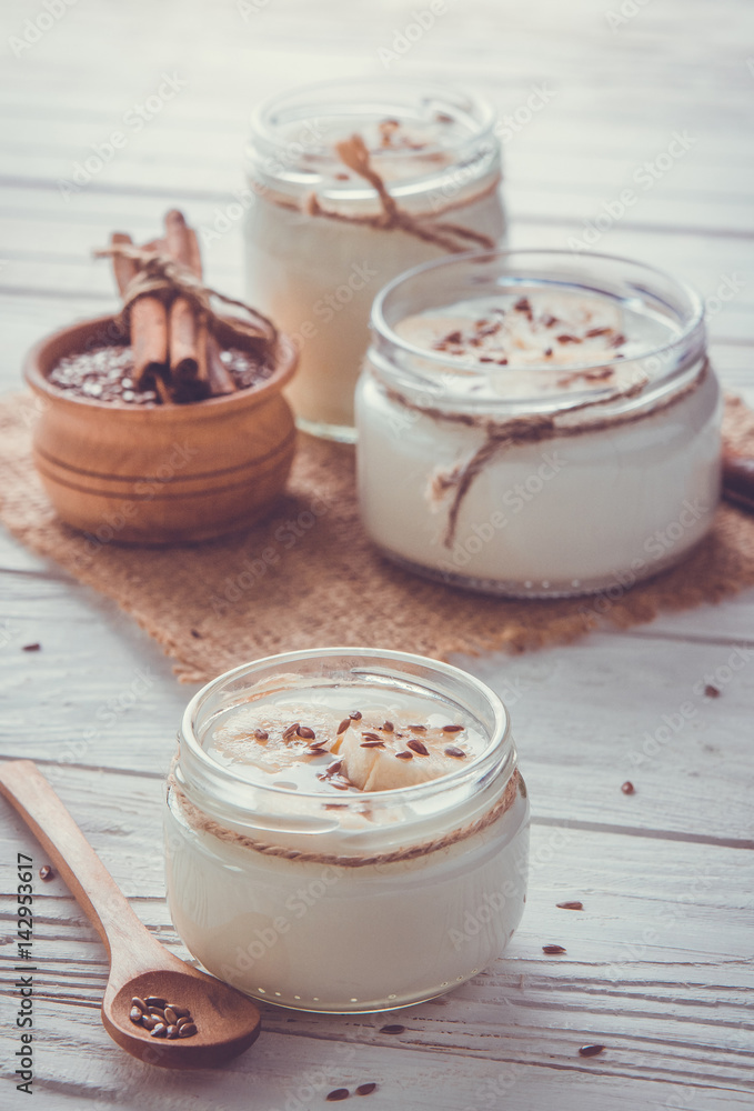 Yogurt in glass jars on wooden background Yogurt in glass jars on wooden background