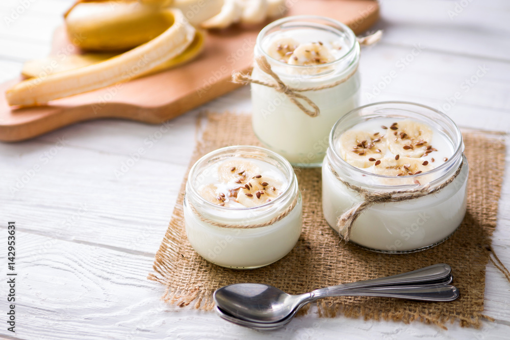 Yogurt in glass jars on wooden background Yogurt in glass jars on wooden background