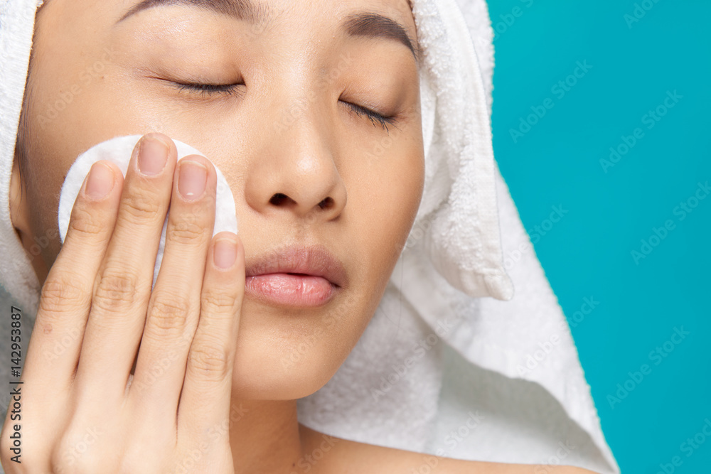 woman wipes her face with a tonic, cotton pad woman wipes her face with a tonic, cotton pad