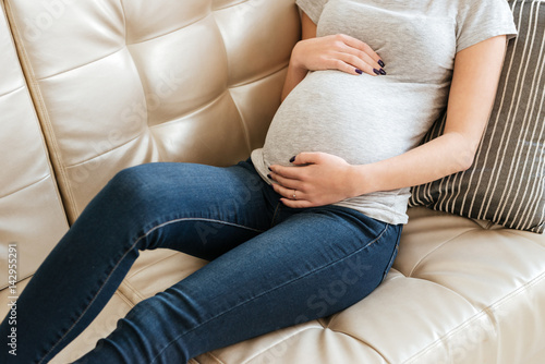 Pregnant young woman lying on couch at home