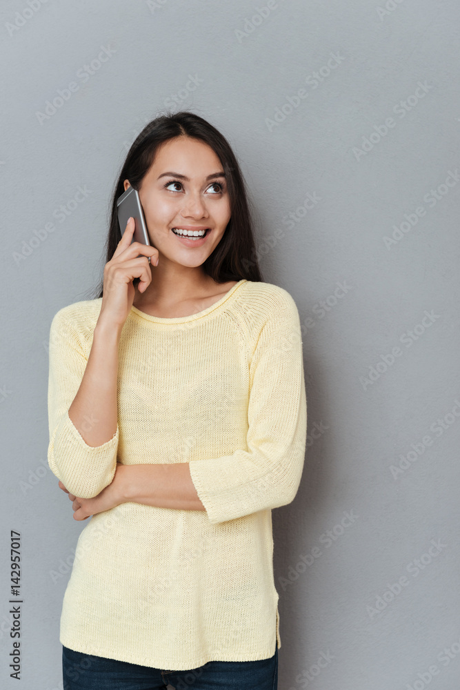 Cheerful cute young woman standing and talking on cell phone Cheerful cute young woman standing and talking on cell phone