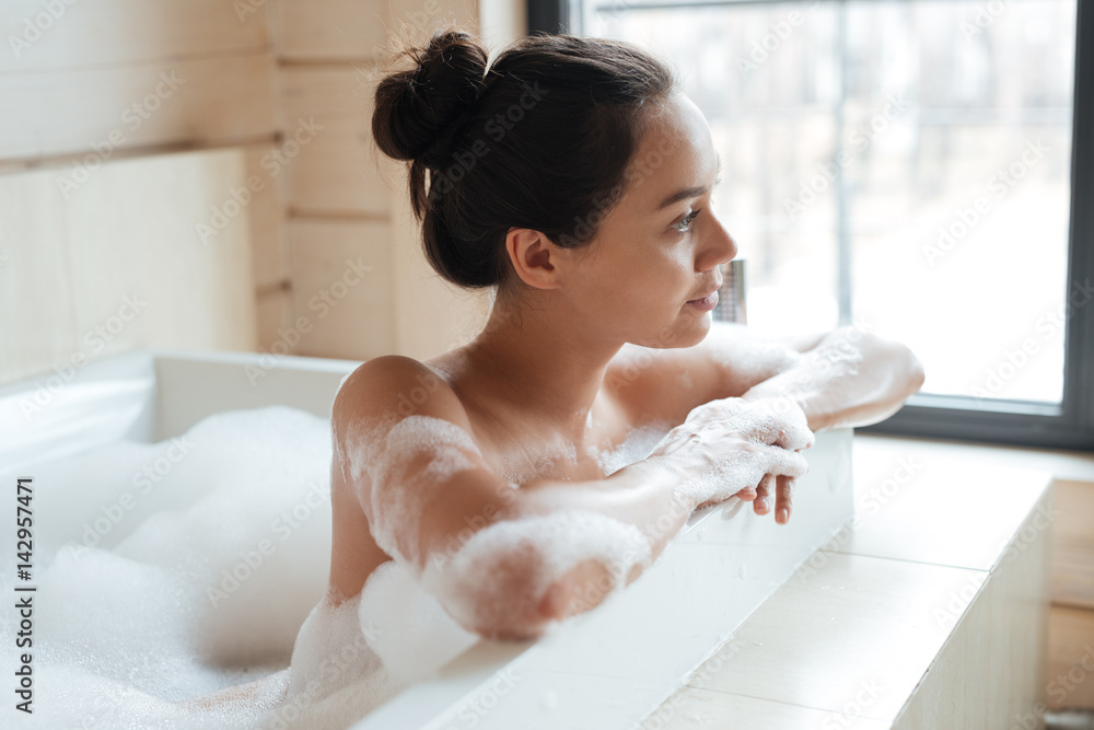 Pensive young woman sitting and thinking in bathtub Pensive young woman sitting and thinking in bathtub