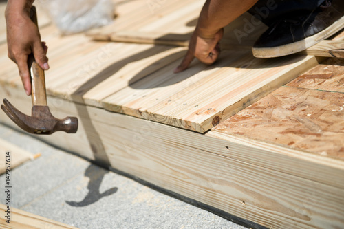 Man laying laminate flooring with tools.