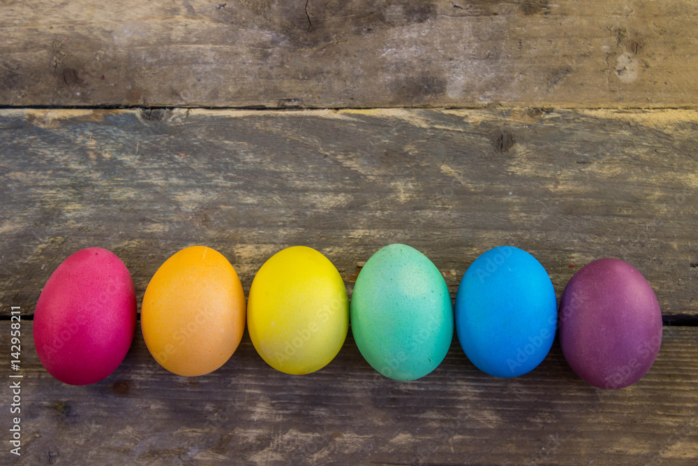 Row of colorful easter eggs on wooden desks Row of colorful easter eggs on wooden desks