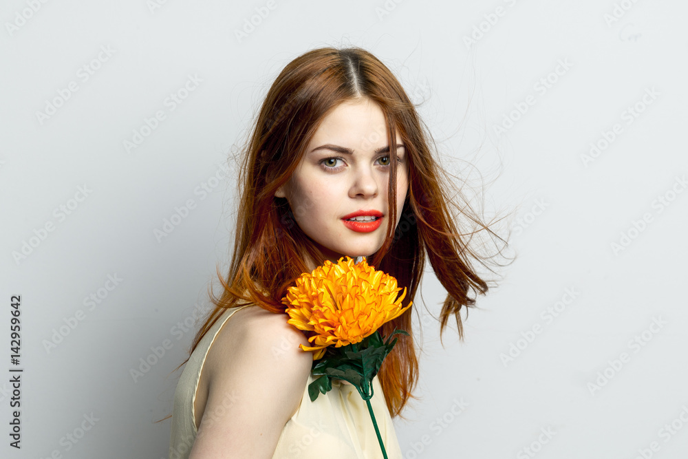 attractive woman with yellow flower stands sideways to the camera attractive woman with yellow flower stands sideways to the camera