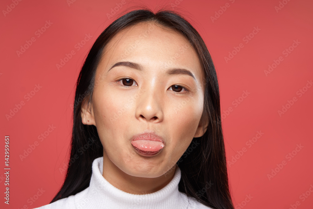 woman with Korean appearance show tongue on red background woman with Korean appearance show tongue on red background