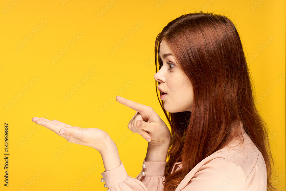 woman on a yellow background shows her hands to the side