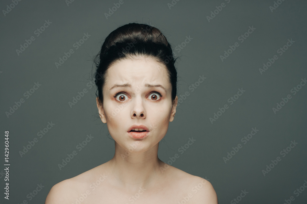 surprised woman with wide eyes and bare shoulders on a gray background surprised woman with wide eyes and bare shoulders on a gray background
