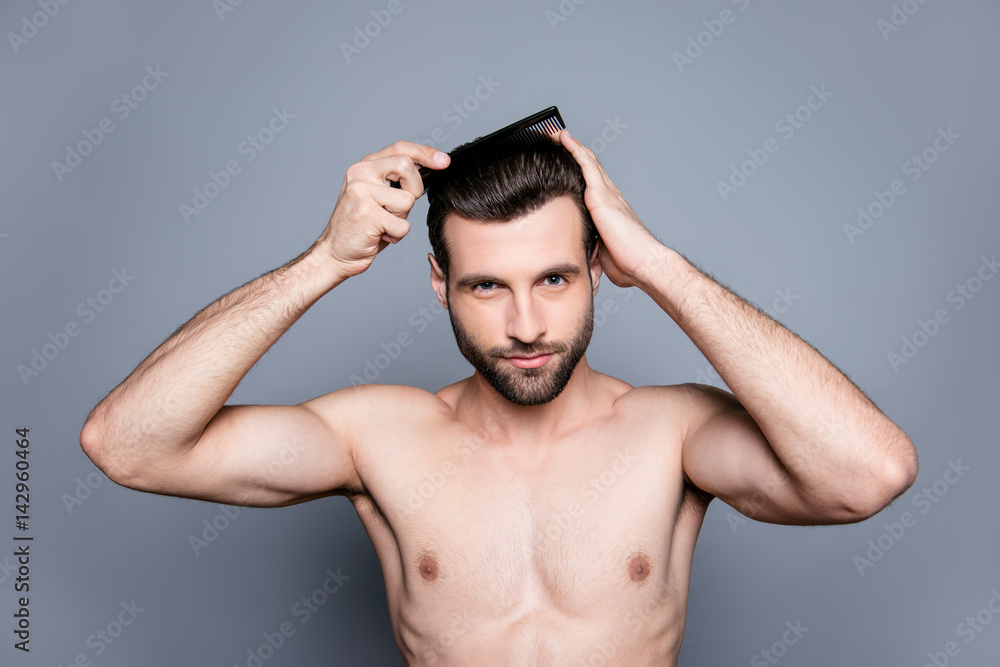 A portrait of a young handsome muscular man combing his hair after taking a shower A portrait of a young handsome muscular man combing his hair after taking a shower