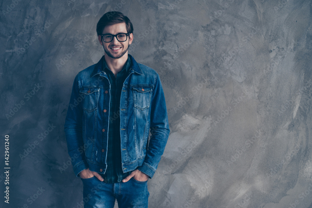 happy trendy young handsome guy in glasses and wearing a denim suit standing on a gray background, smiling and looking directly at the camera happy trendy young handsome guy in glasses and wearing a denim suit standing on a gray background, smiling and looking directly at the camera