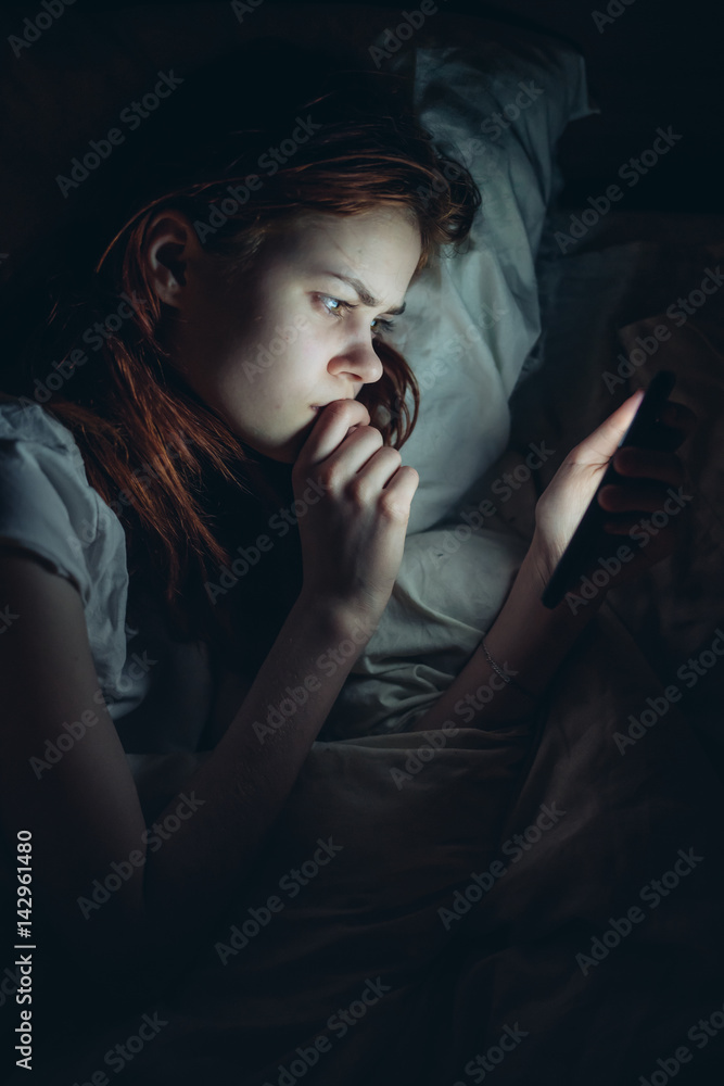 woman looking in the phone lying on the bed woman looking in the phone lying on the bed