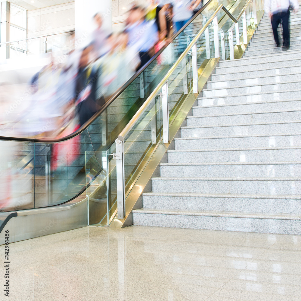 Obraz premium Group of businesspeople moving down on escalator in office. blurred motion.