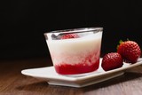 Strawberry flavored tapioca pudding in glass cup on dark wood table and black background