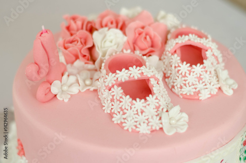 Beautiful pink cake for the birthday girl, close-up. Princess shoes on the cake