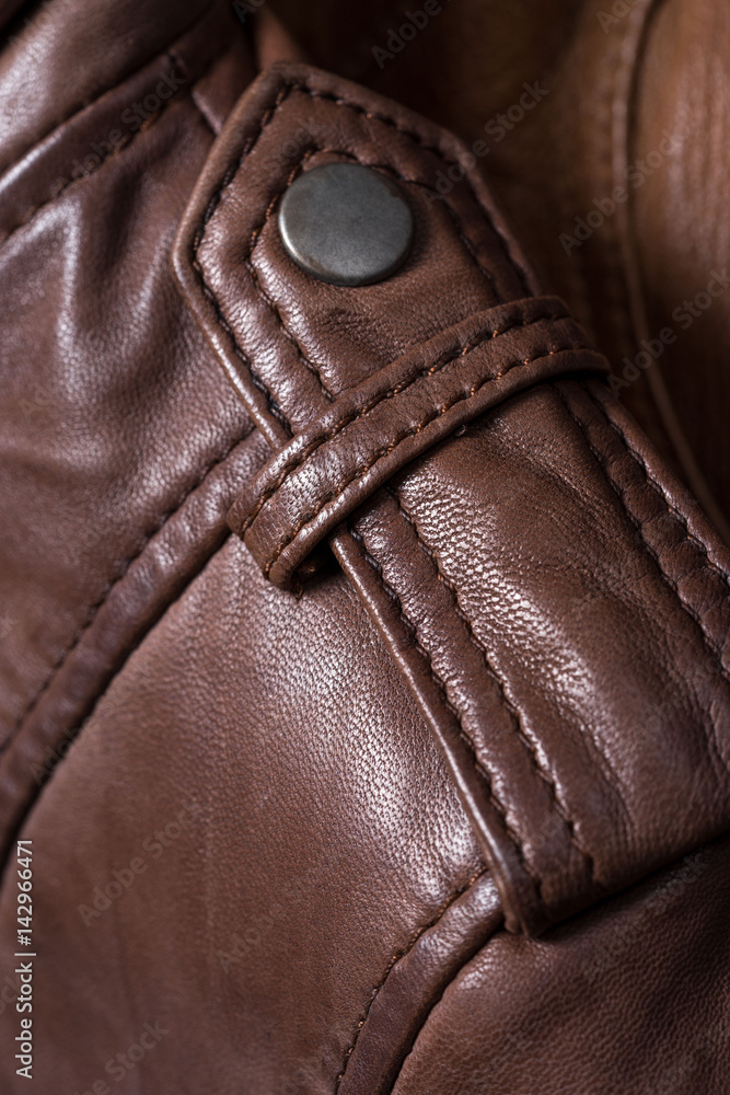 Brown leather jacket shoulder metal clasp button. Macro leather shoulder detail Brown leather jacket shoulder metal clasp button. Macro leather shoulder detail