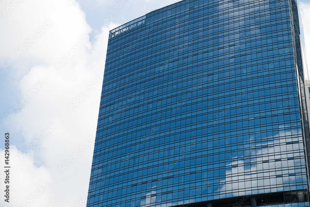 Fototapeta premium Sky and clouds reflected in windows of modern office building.