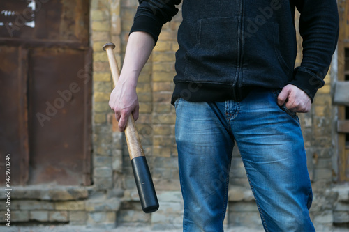 agressive street hooligan is holding a baseball bat