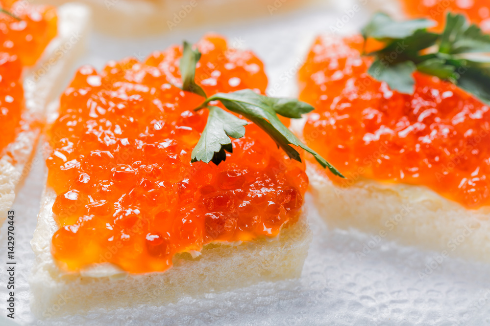 Sandwiches with salmon red caviar and herbs on white napkin. Close up image with selective focus Sandwiches with salmon red caviar and herbs on white napkin. Close up image with selective focus