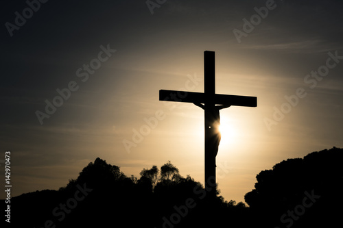 Jesus Christ on the cross silhouette at sunset - crucifixion on the Calvary Hill. Good Friday passion or Lent background.