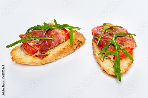 Two bruschettes with serrano ham, cheese and arugula