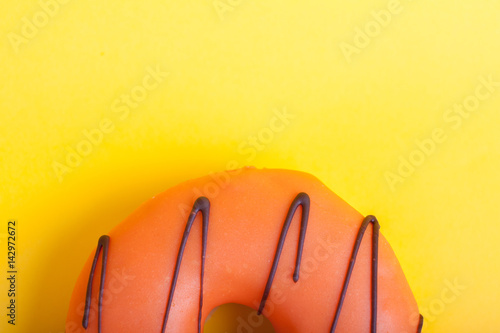 Orange donut with icing on a yellow background. Top view. Minimal concept