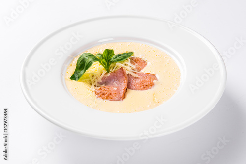 Cream soup with basil, meat steak and cheese on plate.