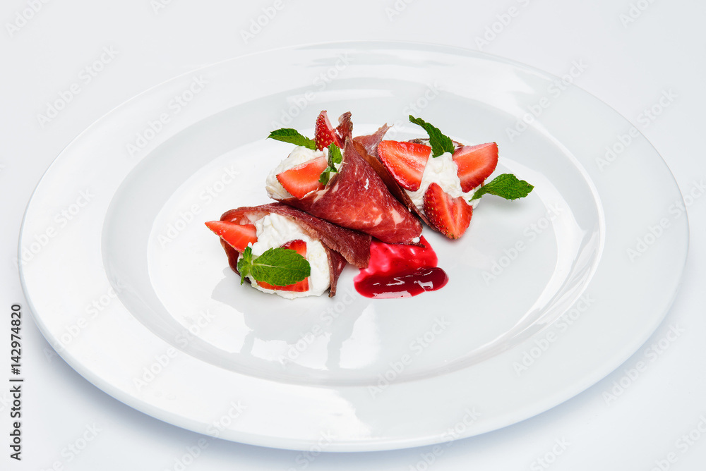 Strawberry and mint in white cream covered with sliced jamon. Strawberry and mint in white cream covered with sliced jamon.