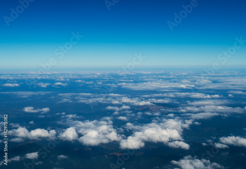 Blue sky with white clouds, view from a flying airplane.