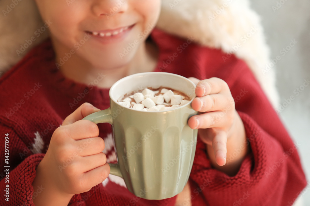 Cute little boy drinking hot chocolate with marshmallow at home, closeup Cute little boy drinking hot chocolate with marshmallow at home, closeup