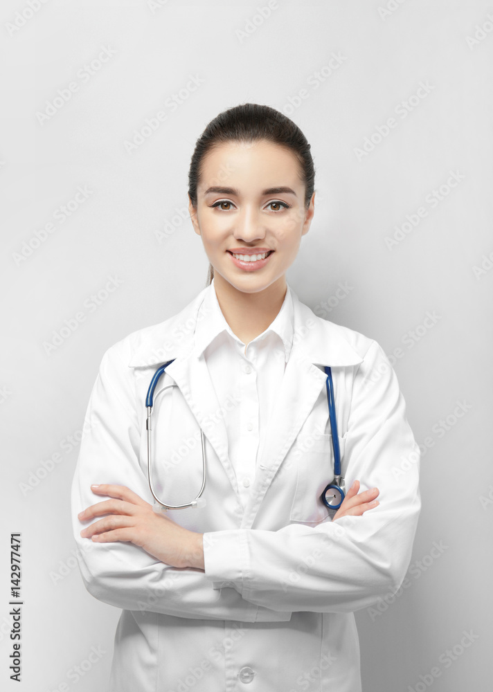 Beautiful young doctor on light background Beautiful young doctor on light background